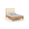 Eichenholz-Doppelbett mit hohem, gepolstertem Kopfteil und hohen Beinen, Seitenansicht.